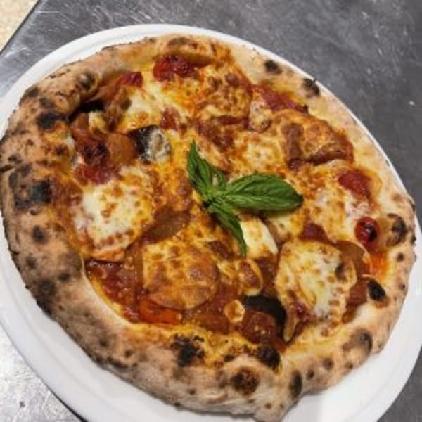 A Neapolitan pizza from Manny's Cucina Napoletana, topped with melted mozzarella, tomato sauce, and basil.