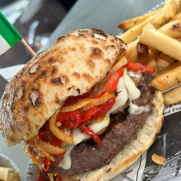 Manny's Italian burger with melted cheese, red peppers, onions, and a side of fries.