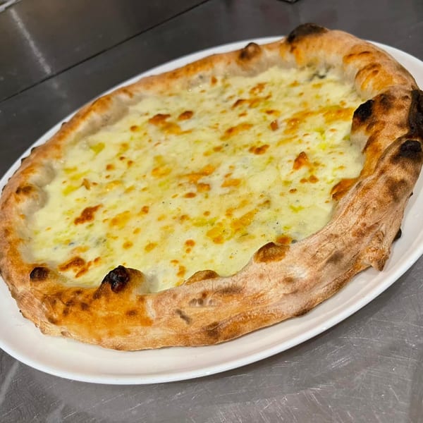 A freshly baked white pizza from Manny's Cucina Napoletana, with a golden crust and melted cheese.
